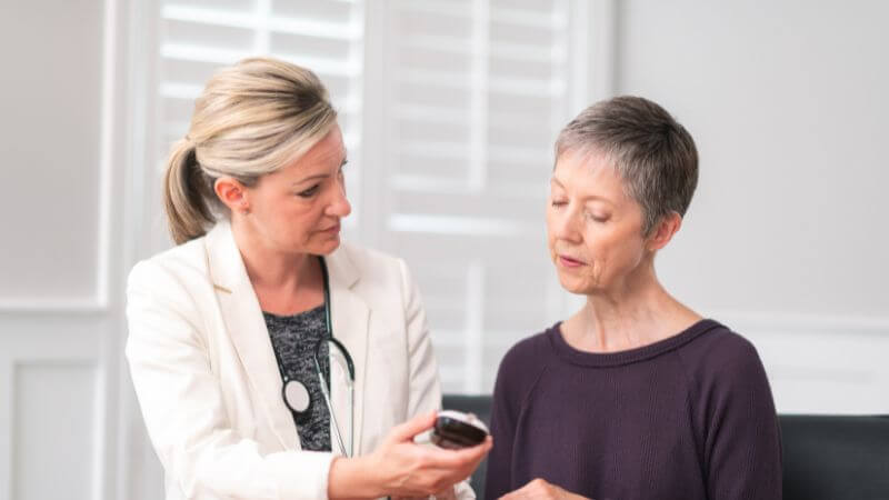 Middle-aged female health care professional showing a BGM to a senior female patient