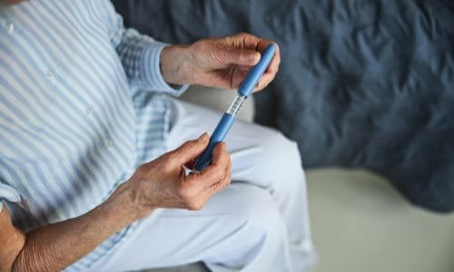 Close-up of female senior citizen sitting & holding an insulin pen in her hands