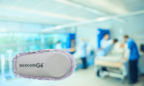 Close-up of Dexcom G6 CGM in foreground of inpatient treatment center with staff & patients in background