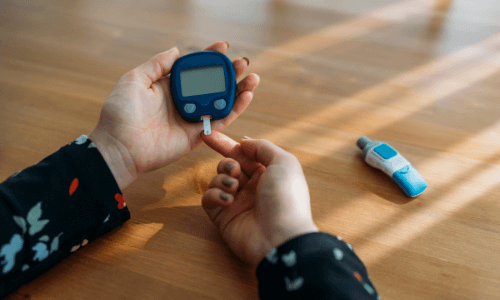 Close-up of female hands on a table testing her blood glucose level with a BGM