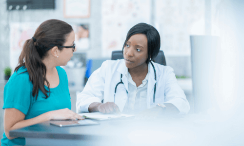 Diverse female health care professional speaking with a female patient in an office setting
