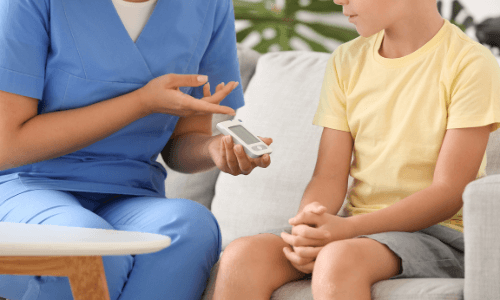 Close-up of female health care professional's hands showing a CGM device to a young boy
