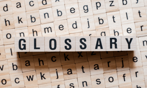 The word Glossary spelled out in Scrabble letters on top of other random Scrabble letters