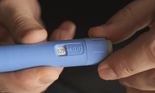 Close-up of hands holding a prefilled incretin pen showing milligram dose