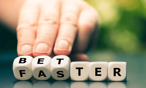 Adult fingers turning over dice spelling the word better & changing it to the word faster
