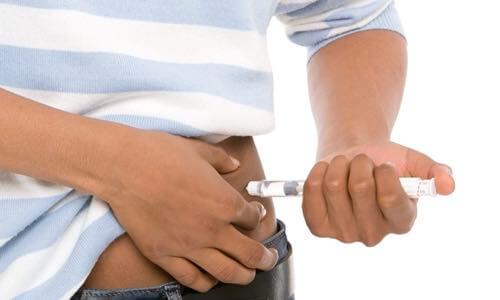 Close-up of diverse young person injecting insulin into the abdomen