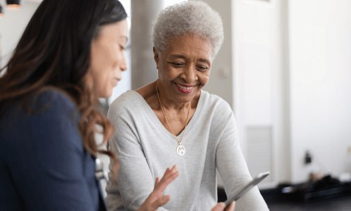Diverse female health care professional shows a diverse senior female patient a smartphone app